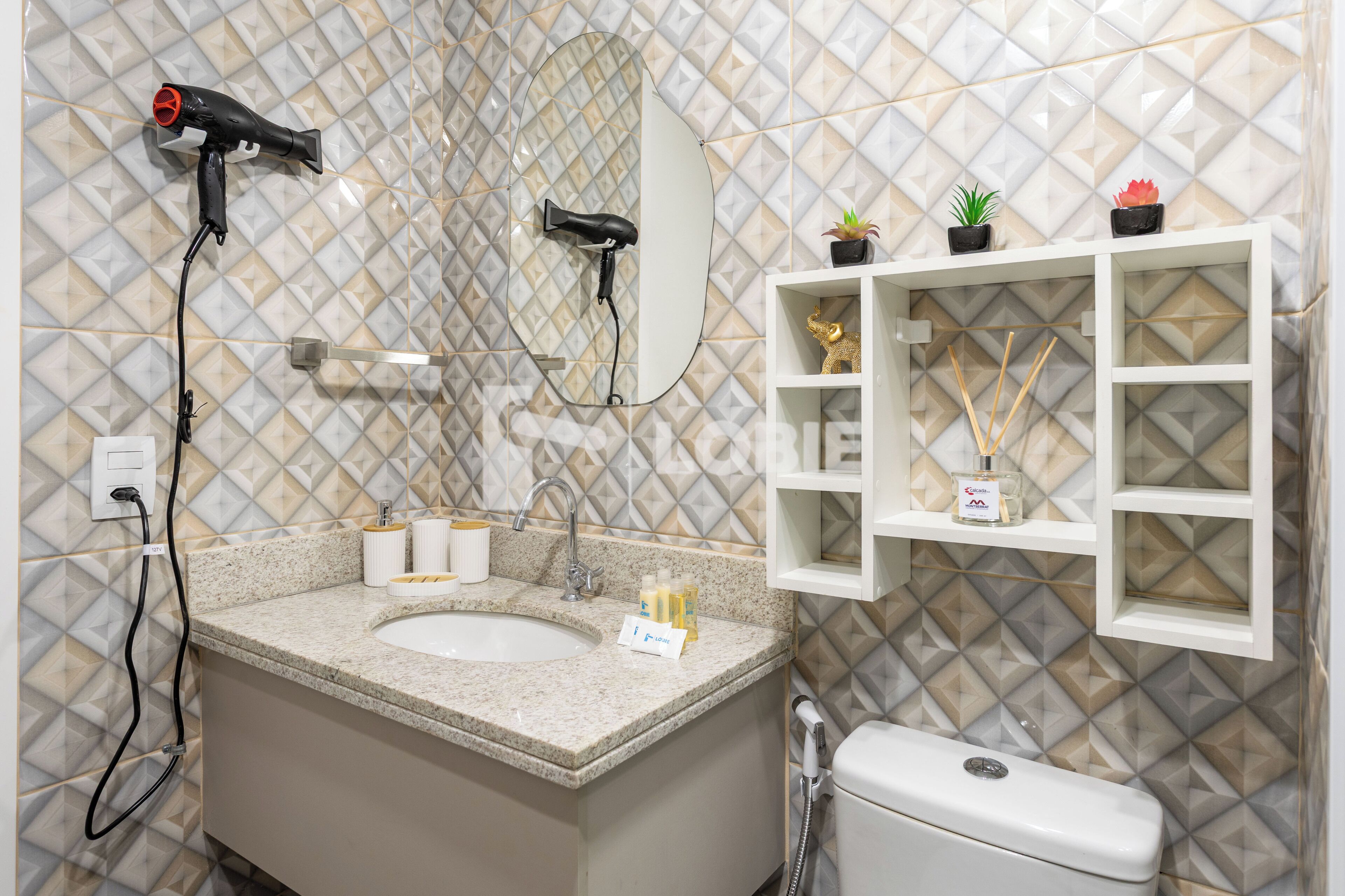 A bathroom with a sink, mirror, hairdryer, and shelves with toiletries.