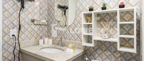 A bathroom with a sink, mirror, hairdryer, and shelves with toiletries.