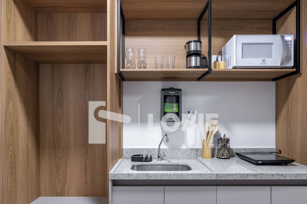 A modern kitchen with a microwave, coffee maker, and utensils on the counter.