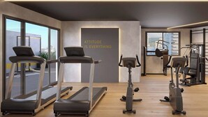 Un gimnasio moderno con cintas de correr, elíptica y una pared con una cita motivacional.