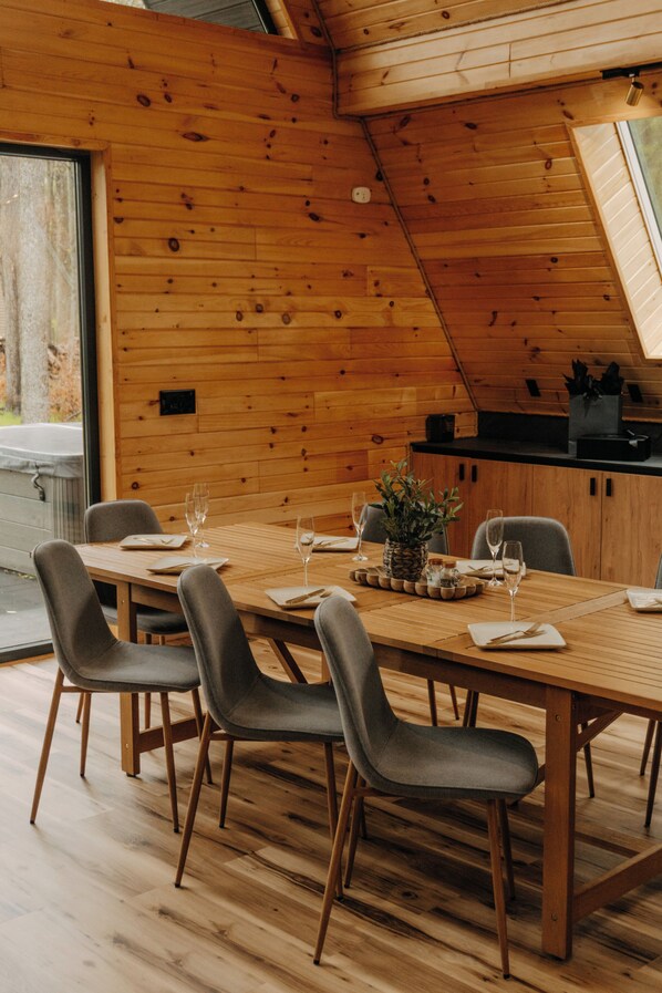 A dining area with a wooden table, four chairs, and a potted plant.