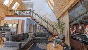 A modern interior with a wooden ceiling, a staircase, a living area with a sofa, and a kitchen in the background. - Pocono A-Frame Retreat • Lake • Hot Tub • Sauna (Coolbaugh Township)