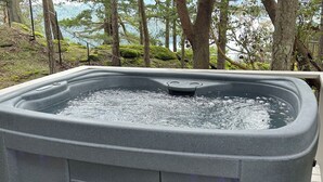 A hot tub on a deck with a view of trees and a body of water. - Welcome to Cloud 99! Cabin has privacy, quiet, awesome view! Recently updated. (Mayne Island)