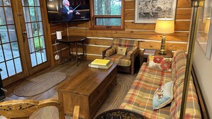 A cozy cabin interior with a wooden interior, a television, a plaid sofa, and a small table. - Welcome to Cloud 99! Cabin has privacy, quiet, awesome view! Recently updated. (Mayne Island)