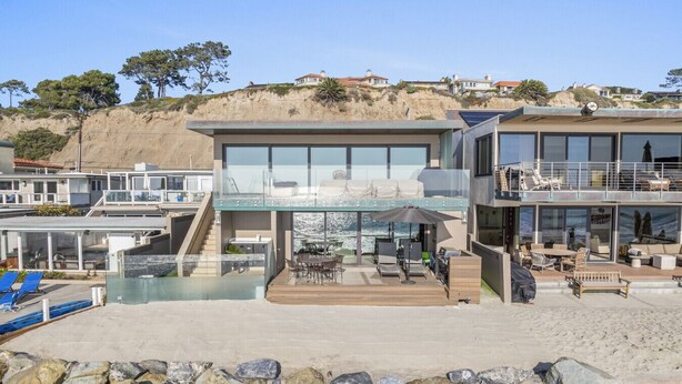 Een modern pand aan het strand met een groot zwembad, terras en uitzicht op de zee.