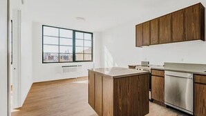 Een moderne keuken met houten kastjes, een roestvrijstalen vaatwasser en een groot raam dat voor natuurlijk licht zorgt.