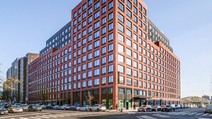 Een modern gebouw van rode baksteen met een ruitpatroon van ramen en een plat dak.
