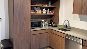 Een moderne keuken met houten kastjes, een magnetron, een koffiezetapparaat en een vaatwasser.