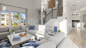 Ein modernes Wohnzimmer mit Sofa, Couchtisch und einer Treppe, die in eine Küche führt.