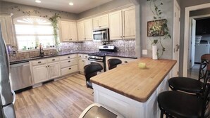 A kitchen with light-colored cabinets, a granite countertop, a wooden island, and a stainless steel refrigerator. - Huge Smart-Home 3ponds fishing 3.5 mi to OU in Norman, pool, outdoor patio, PETS (Norman)