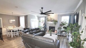A modern living room with a sectional sofa, a dining table with chairs, a fireplace, and a ceiling fan. - Huge Smart-Home 3ponds fishing 3.5 mi to OU in Norman, pool, outdoor patio, PETS (Norman)