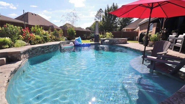A swimming pool with clear water, surrounded by stone walls and a red umbrella. - Huge Smart-Home 3ponds fishing 3.5 mi to OU in Norman, pool, outdoor patio, PETS (Norman)