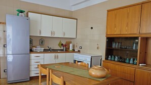 Une cuisine avec une table en bois, des chaises, un réfrigérateur, des placards et une cuisinière.