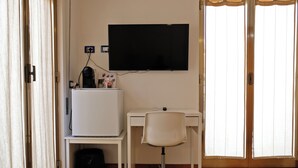 Une petite pièce comprenant un bureau, une chaise et un téléviseur fixé au mur.