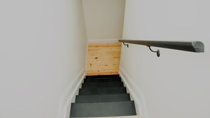Una escalera con piso de madera y escalones negros, que sube.