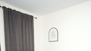 Un dormitorio con una cama, cortinas grises, una mesita de noche y una cita enmarcada en la pared.