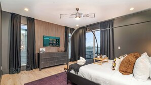Een moderne slaapkamer met een bed, een televisie en uitzicht op het groen.