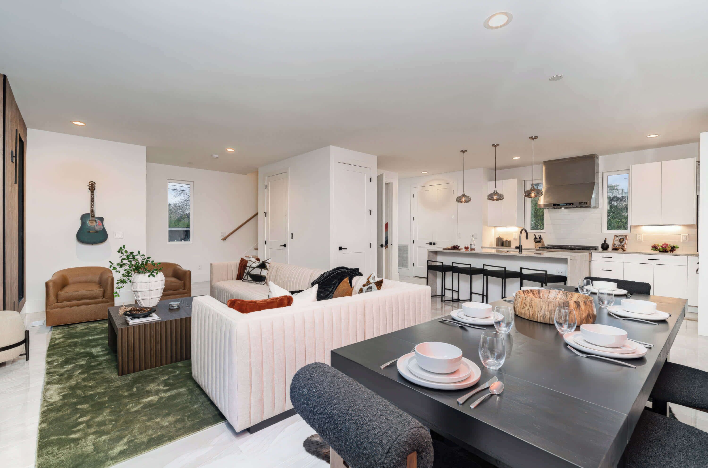 A modern living room with a sofa, coffee table, and dining table set for a meal.
