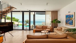 A modern living room with a large leather sofa, a dining area, and a view of the sea. - Villa Katina - Four bedroom Vila with pool and hot tub (Sucuraj)
