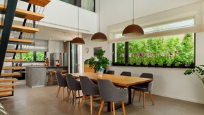 A modern kitchen with a central island, a dining area with a wooden table and chairs, and a large window with a view of greenery. - Villa Katina - Four bedroom Vila with pool and hot tub (Sucuraj)