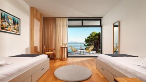 A modern hotel room with two beds, a round rug, a small table with chairs, and a large window offering a view of the sea. - Villa Katina - Four bedroom Vila with pool and hot tub (Sucuraj)