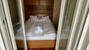 Ein Einzelbett mit Holz-Kopfteil, weißer Bettwäsche und zwei Handtüchern.