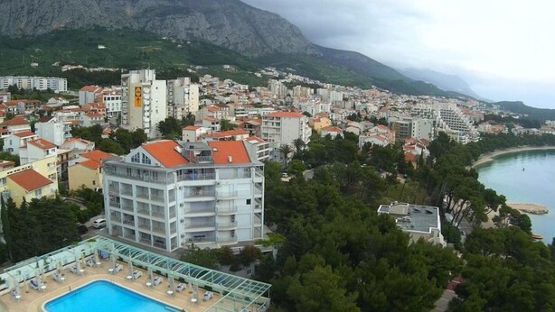 Eine Küstenstadtansicht mit einem markanten Hotel, das einen Pool auf dem Dach und Meerblick bietet.