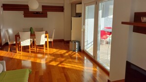 A spacious living area with a wooden floor, a dining table with chairs, a large sliding glass door leading to an outdoor patio, and a ceiling light fixture. - Villa Nižić Makarska - One Bedroom Apartment With Balcony (Marina) (Makarska)
