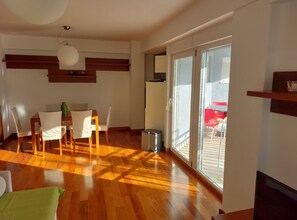 A spacious living area with a wooden floor, a dining table with chairs, a large sliding glass door leading to an outdoor patio, and a ceiling light fixture. - Villa Nižić Makarska - One Bedroom Apartment With Balcony (Marina) (Makarska)