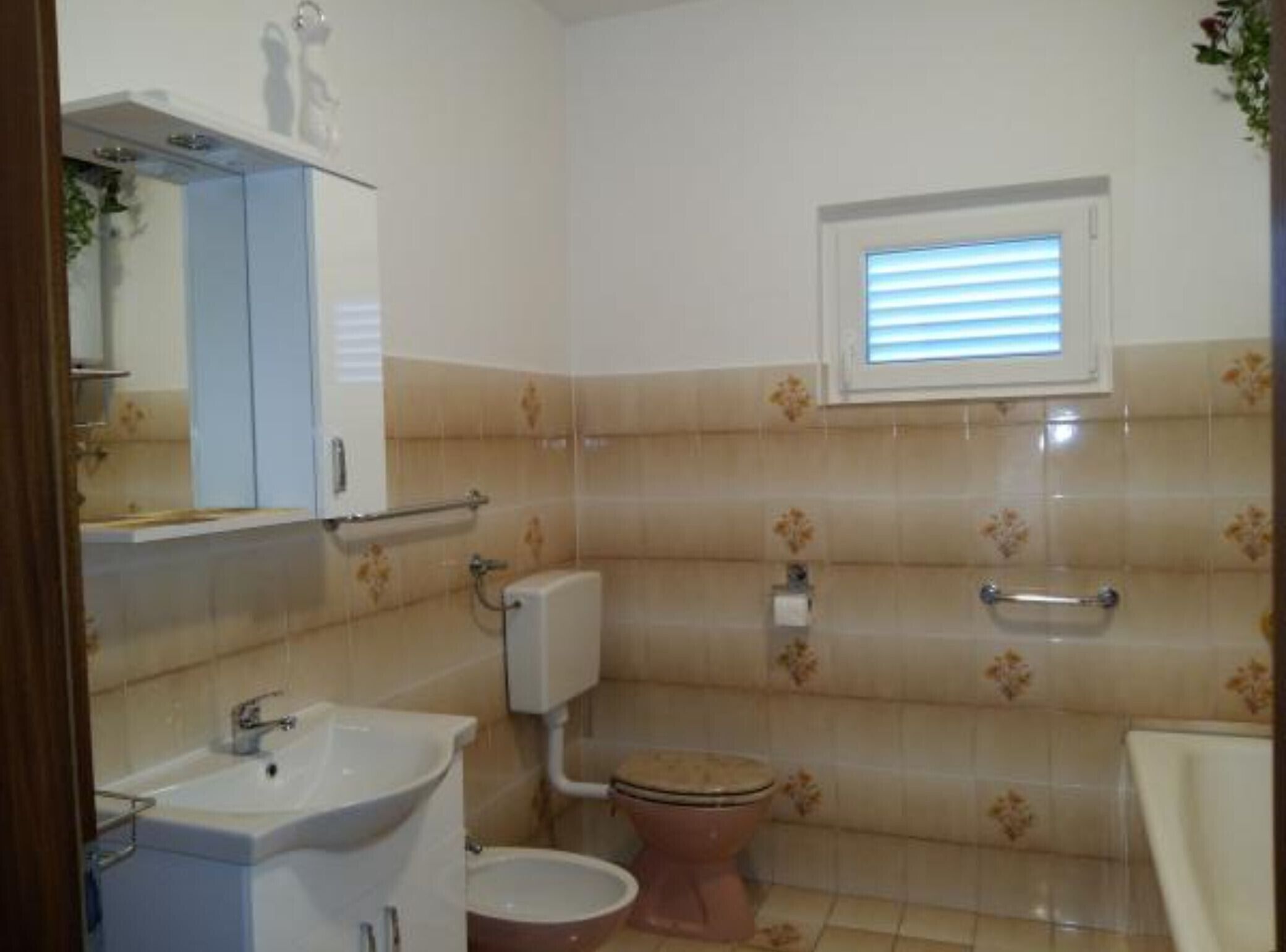 Une salle de bain avec un lavabo, des toilettes et une fenêtre.