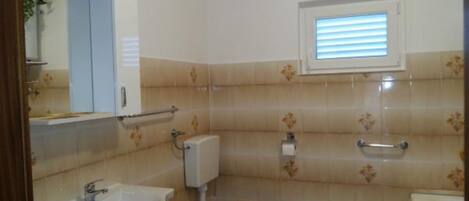Une salle de bain avec un lavabo, des toilettes et une fenêtre.