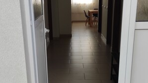 Ein schmaler Korridor mit Fliesenboden, der zu einem Essbereich mit Tisch und Stühlen führt.