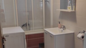 Ein kleines Badezimmer mit Dusche, Waschbecken und Toilette.