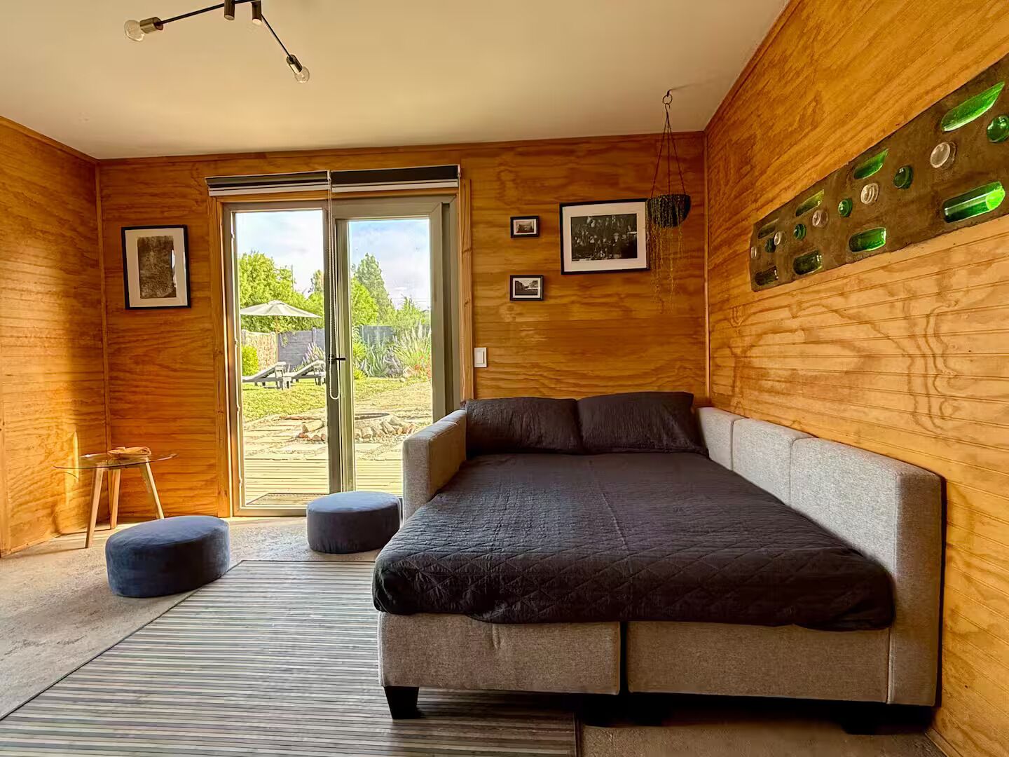 A modern room with a large bed, a glass table, and a view of the outdoors.