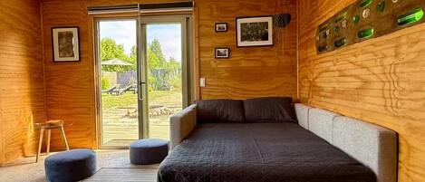 A modern room with a large bed, a glass table, and a view of the outdoors.