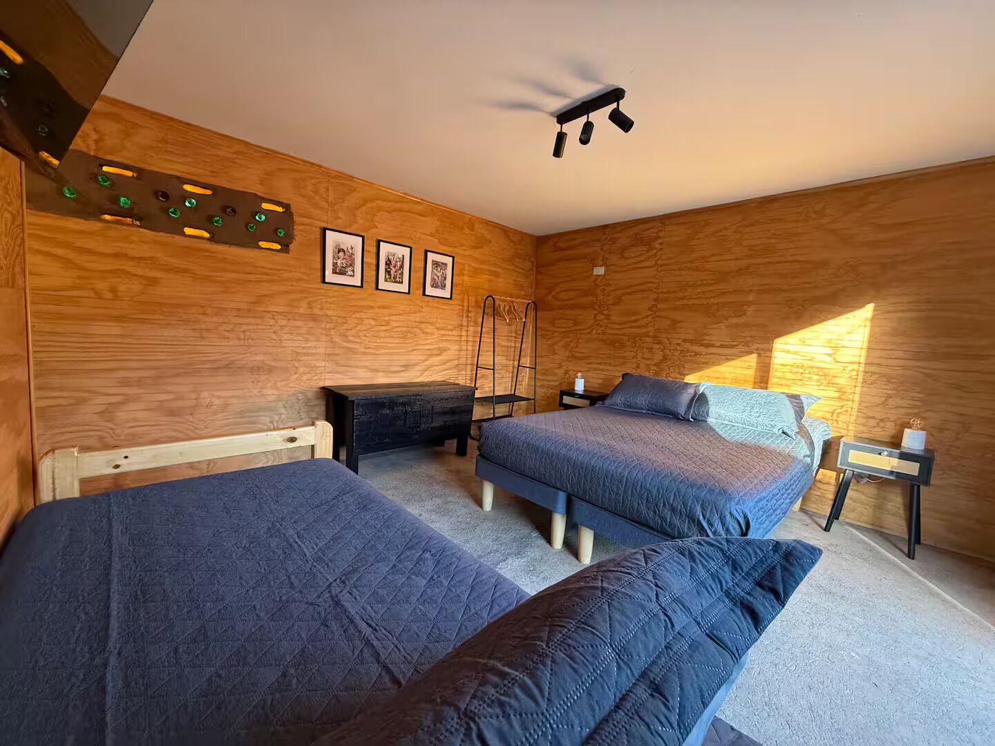 A room with wooden walls, two beds, a ladder, and a ceiling light fixture.