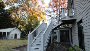 Une maison blanche avec un escalier en bois menant à un balcon.