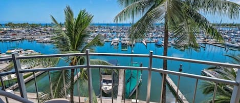 A balcony with a view of a marina and palm trees.