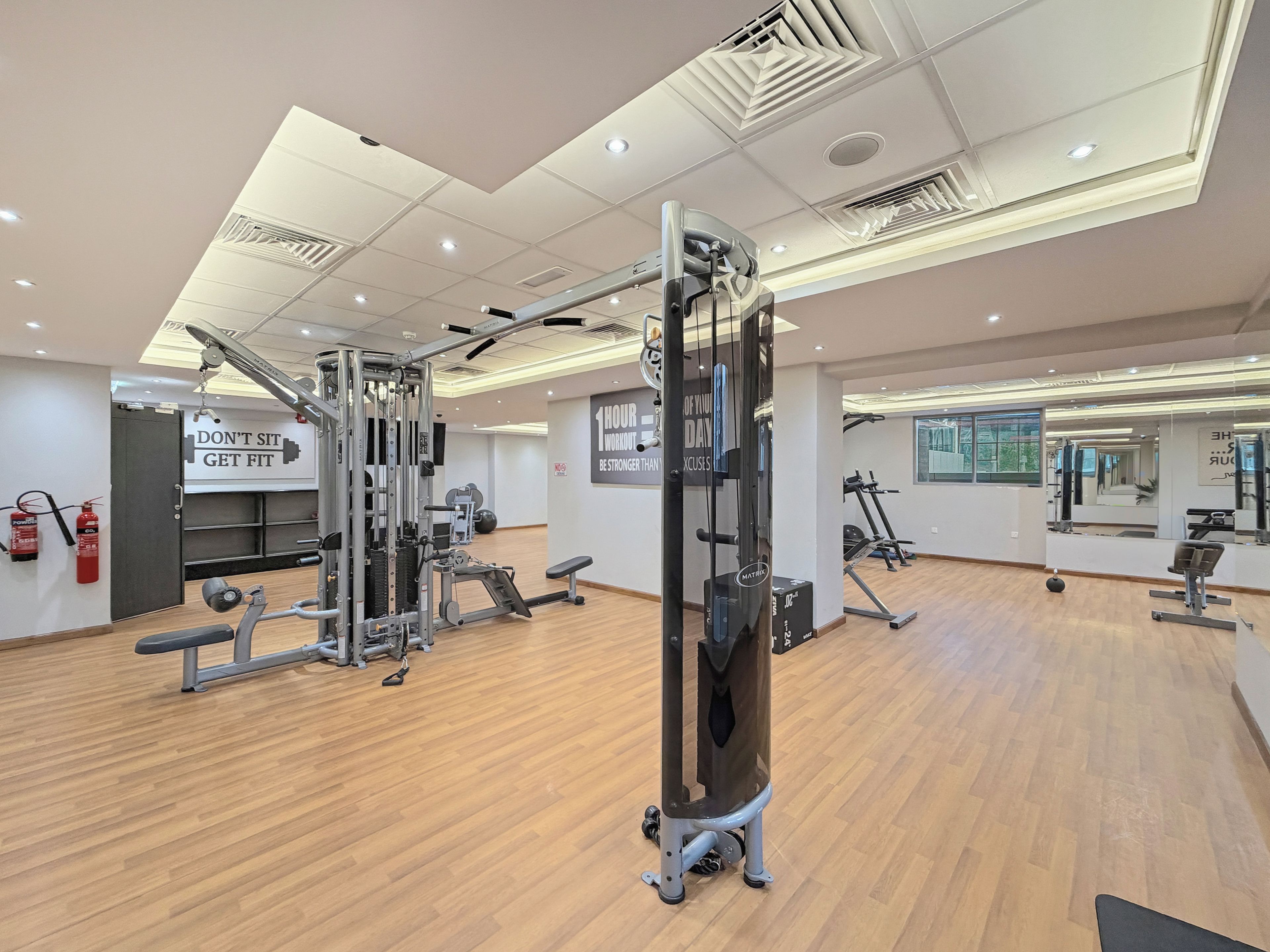 A gym with various exercise equipment, a fire extinguisher, and motivational wall text.