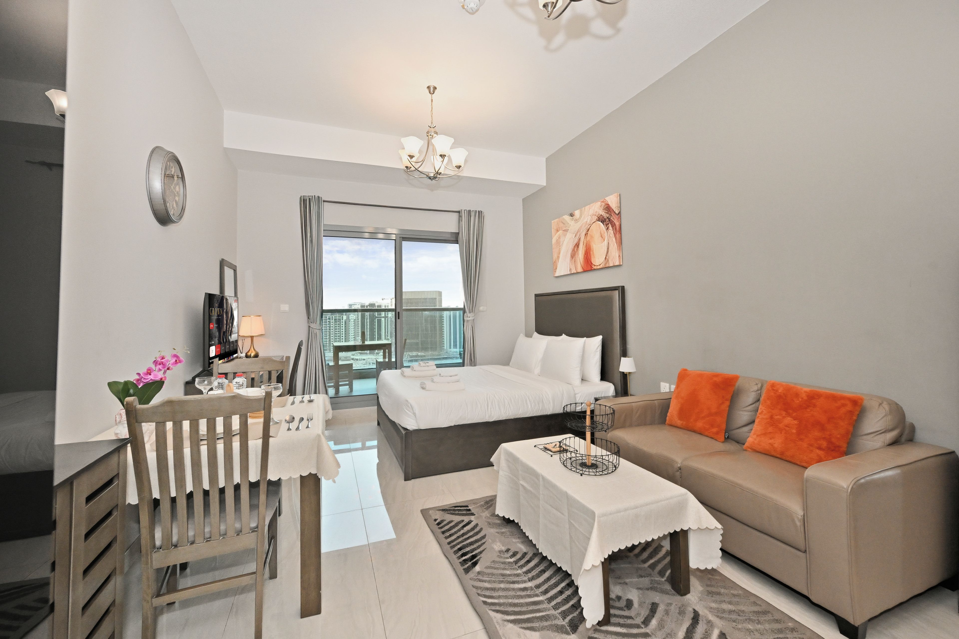 Ein modernes Hotelzimmer mit Bett, Sofa, Esstisch und Blick auf die Stadt.