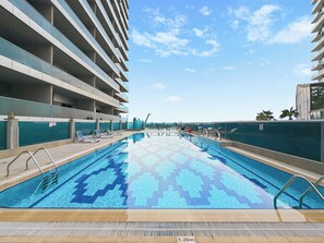 A swimming pool with a tiled pattern, surrounded by a building with multiple balconies. - 1306 Bloomfields Casual STU Elite Tower  (Dubai)