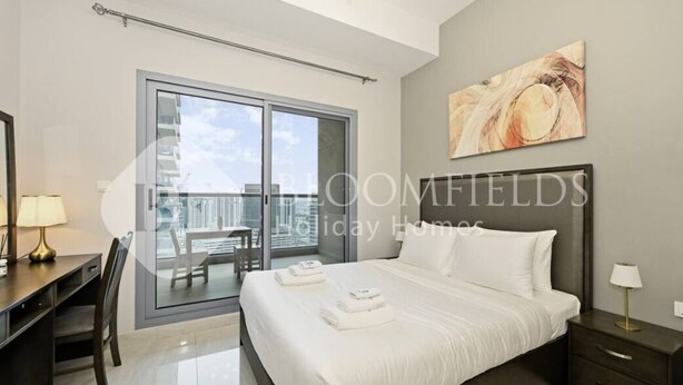 Ein modernes Hotelzimmer mit einem großen Bett, einem Schreibtisch und einem Balkon mit Blick auf die Stadt.