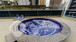 Ein Whirlpool mit steinverkleideter Außenwand, umgeben von einer gefliesten Terrasse.