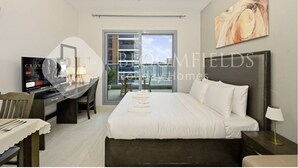 Ein Hotelzimmer mit einem Bett, einem Schreibtisch mit Computer, einem Esstisch und einem großen Fenster.