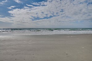Ein Strand mit klarem Himmel und Wellen im Meer.