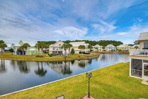 A waterfront residential area with houses, a calm lake, and a well-maintained lawn. - Spacious Home w/ Oceanside Village Resort Perks! (Murrells Inlet)