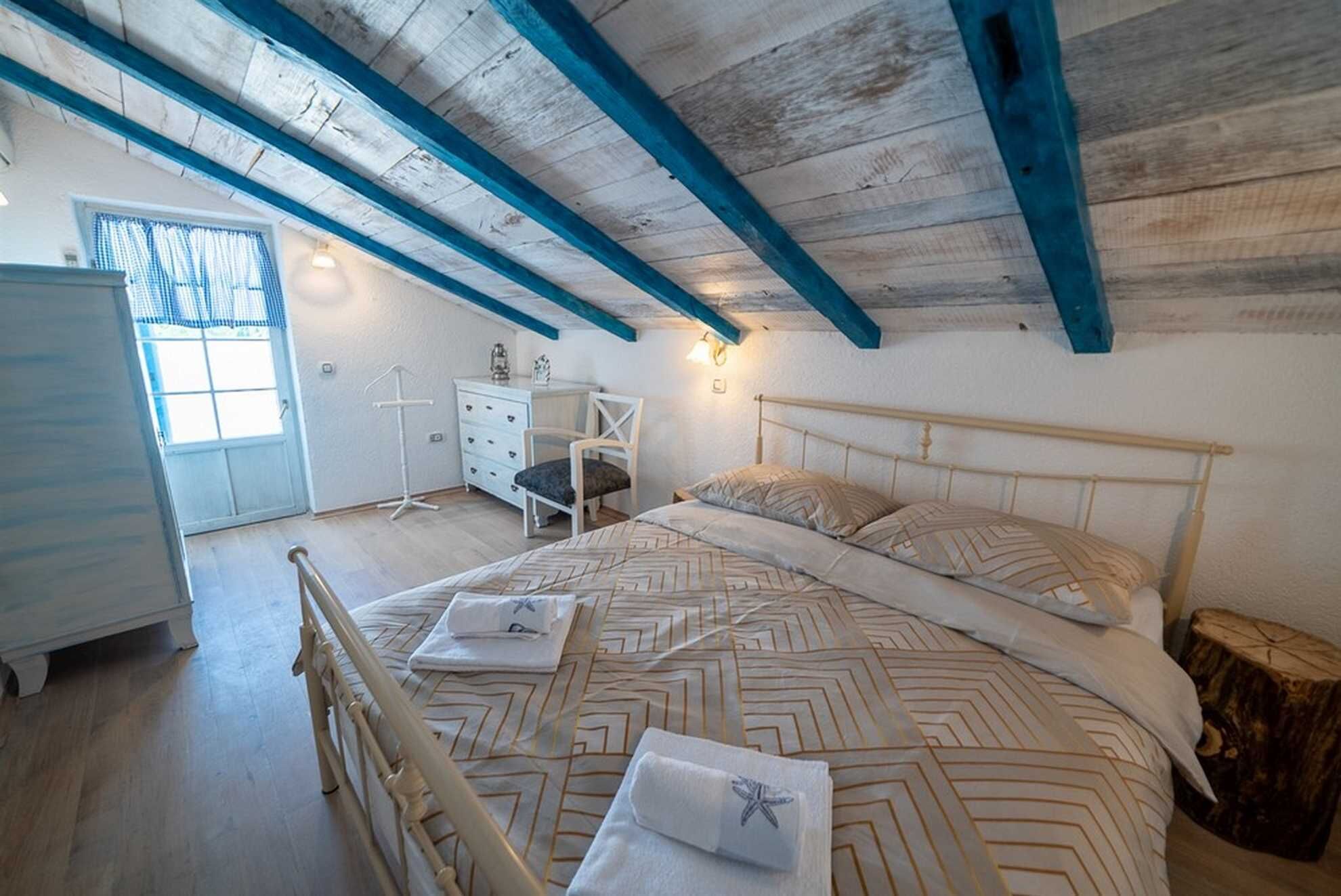 Une chambre à coucher avec un lit, une commode, une chaise et une fenêtre.
