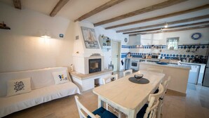 Un salón acogedor con chimenea, una mesa de comedor y una cocina con azulejos azules y blancos.