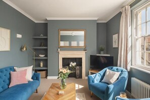 A living room with a fireplace, two blue armchairs, a sofa, and a television. - Lovely Maisonette in Centre of City w/ Parking (Bath)