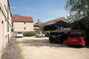 A gravel driveway with parked cars and a building with a red-tiled roof.